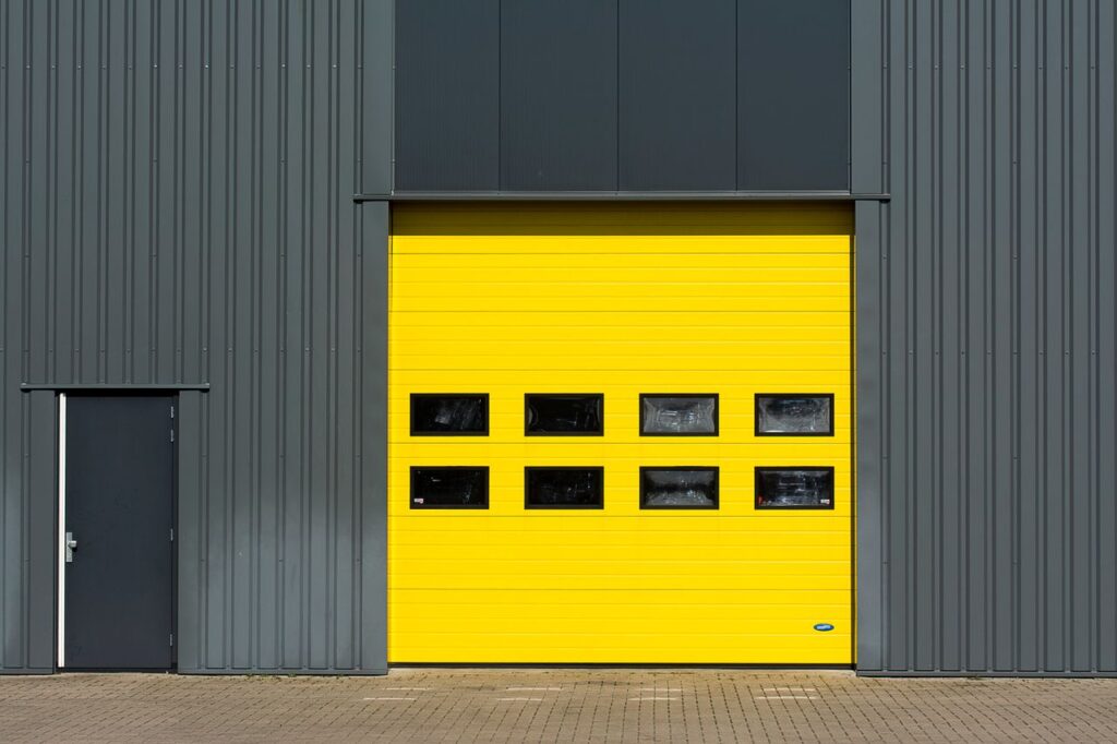 pexels photo 9302309 A sleek industrial structure featuring a vibrant yellow garage door for architectural interest.